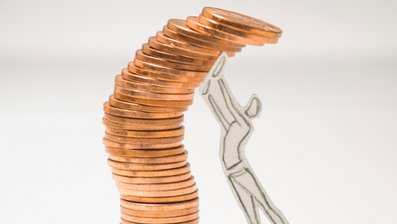 mini person trying to hold back toppling coins