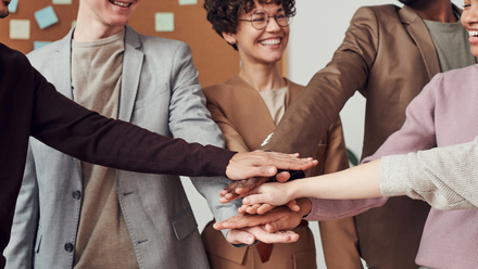 Group of adults putting their hands together like a team